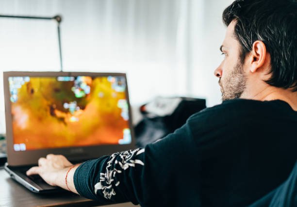 Young man playing games on laptop while staying home during COVID-19 pandemic