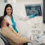 Female dentist showing a teeth x-ray to a male patient in a dental clinic